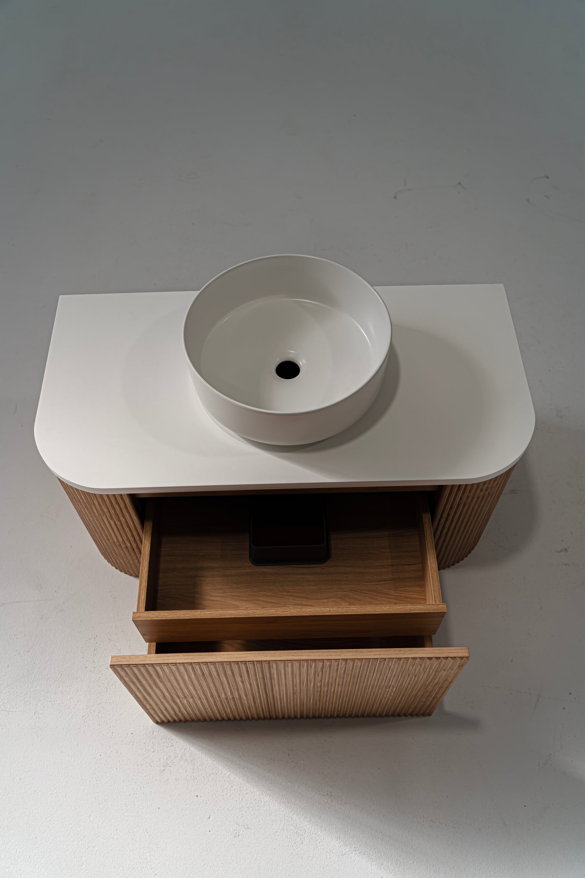 A Portofino Oak Flute Vanity Unit with a white solid surface benchtop and a matte white ceramic basin, featuring a wood grain finish and a modern design.