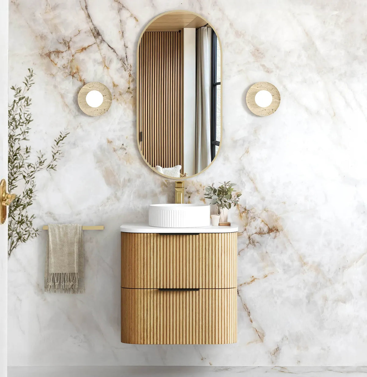 Marble bathroom with a fluted oak wall-hung vanity, round basin, brass tap and oval shaving cabinet